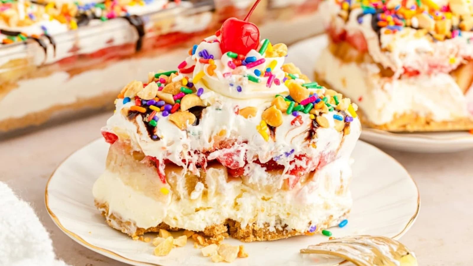 Banana split dessert layered with fruit, cream, and chocolate topping.