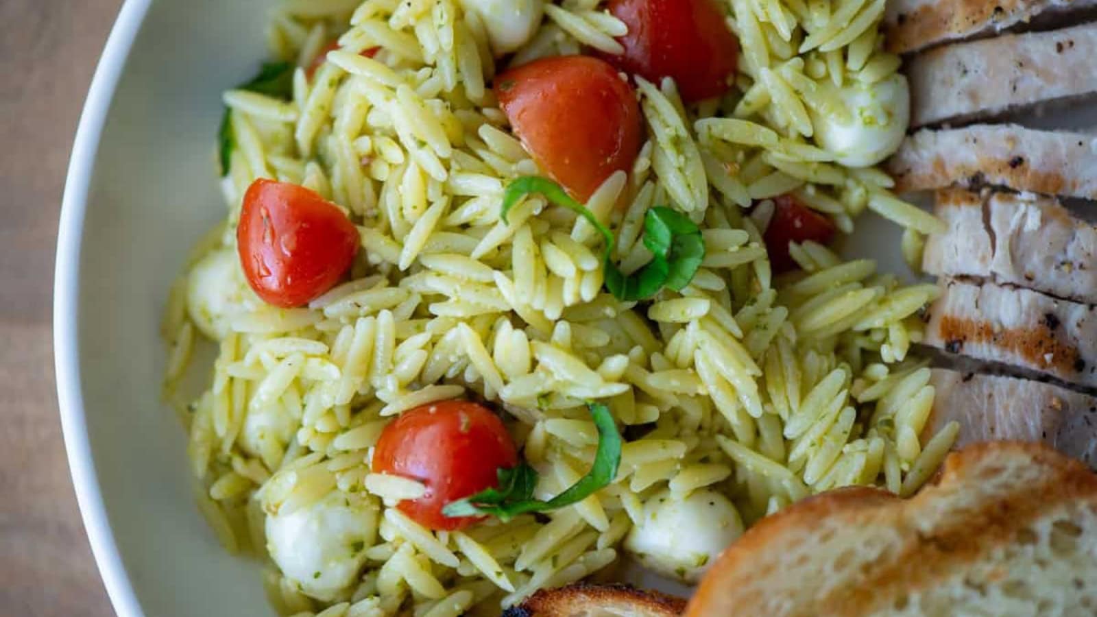 Orzo pasta salad tossed with pesto and fresh ingredients.