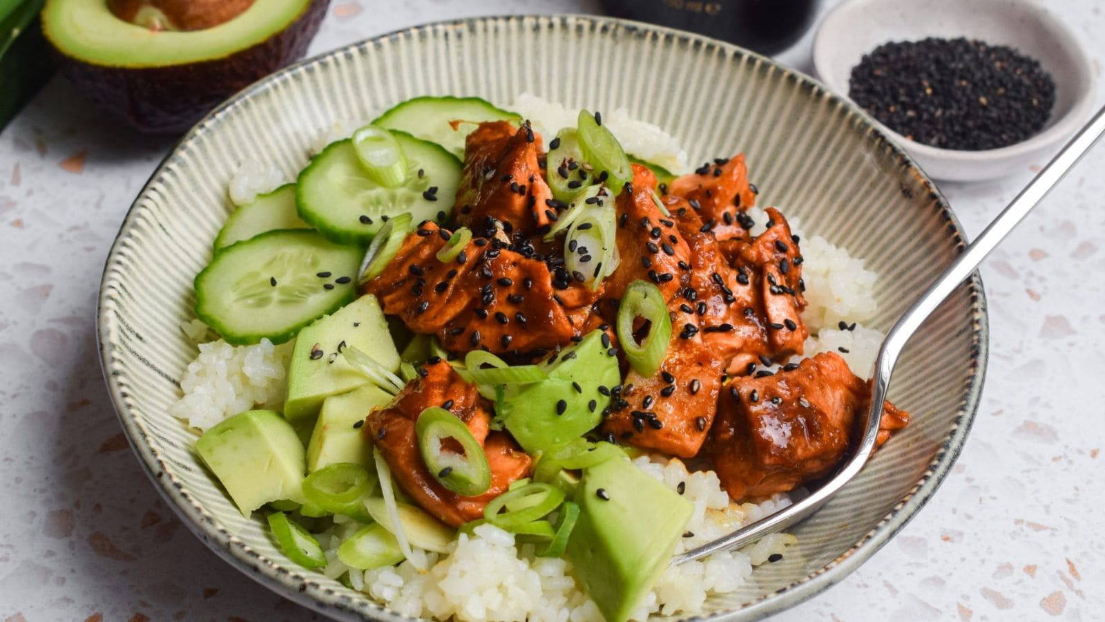 Salmon trout rice bowls served with avocado and spicy sauce over rice.