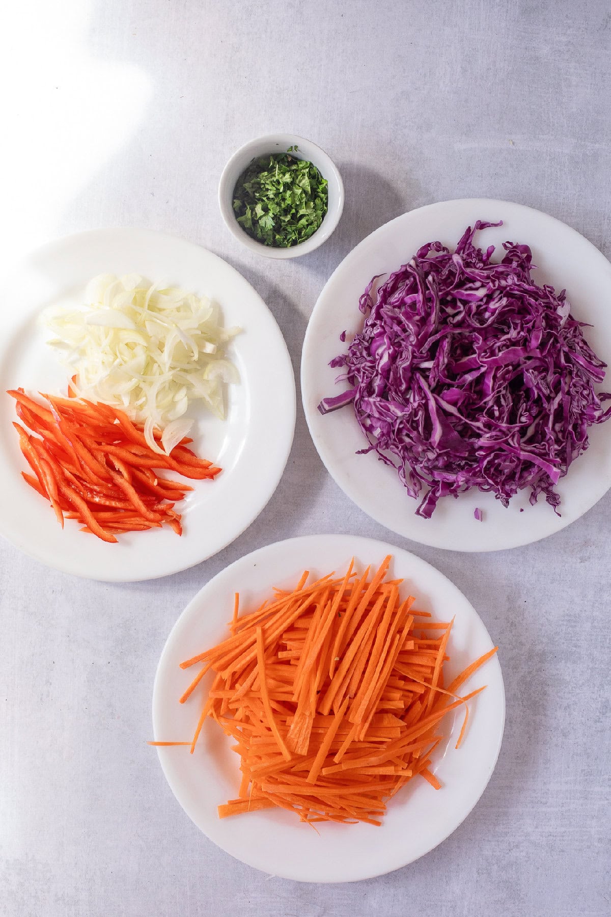 Prepared vegetables for spring roll in a bowl with shredded cabbage, carrots, onions, and red bell pepper.