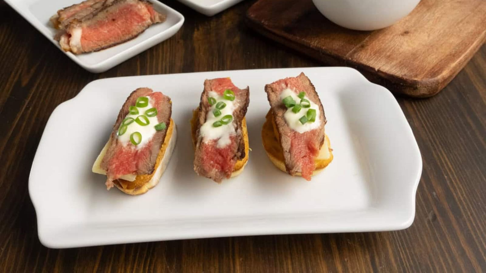 Crostini topped with steak slices, peaches, and garlic on toasted bread.