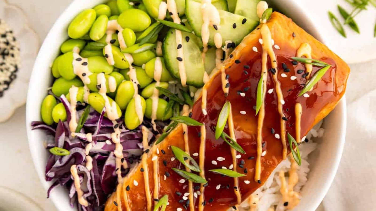 Salmon bowl served with rice and drizzled with teriyaki glaze.