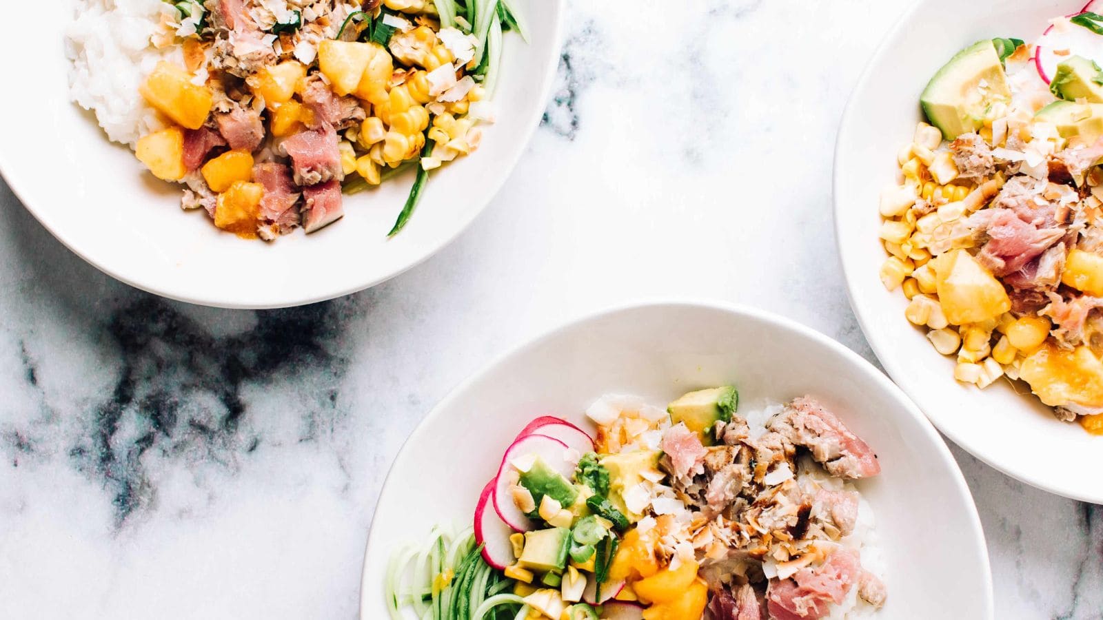 Tuna poke bowls layered with coconut rice and fresh toppings.