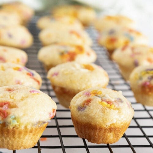 Birthday cake mini muffins with rainbow sprinkles are cooling on a wire rack.