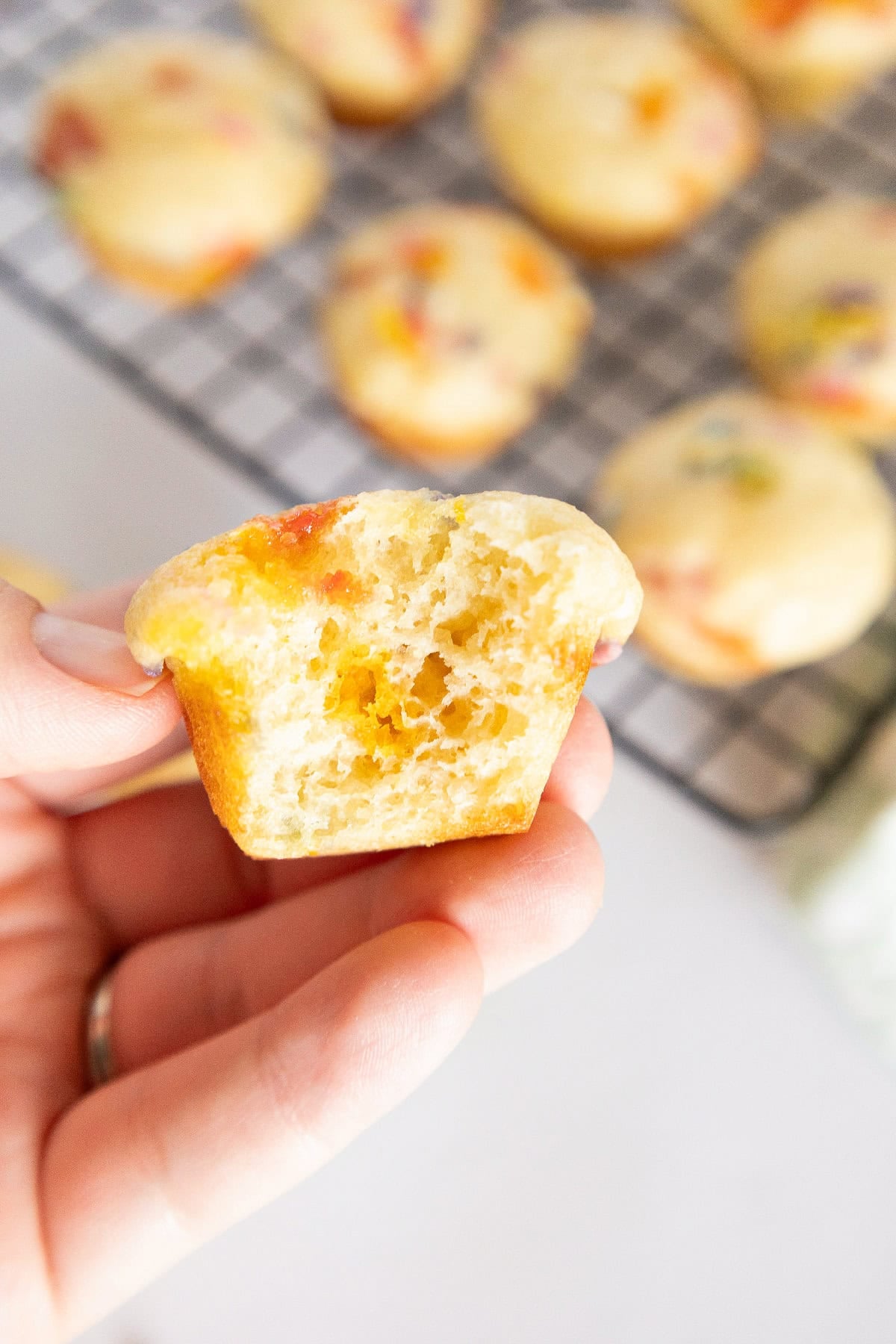 Bitten birthday cake mini muffin showing soft fluffy texture and colorful candy pieces inside.