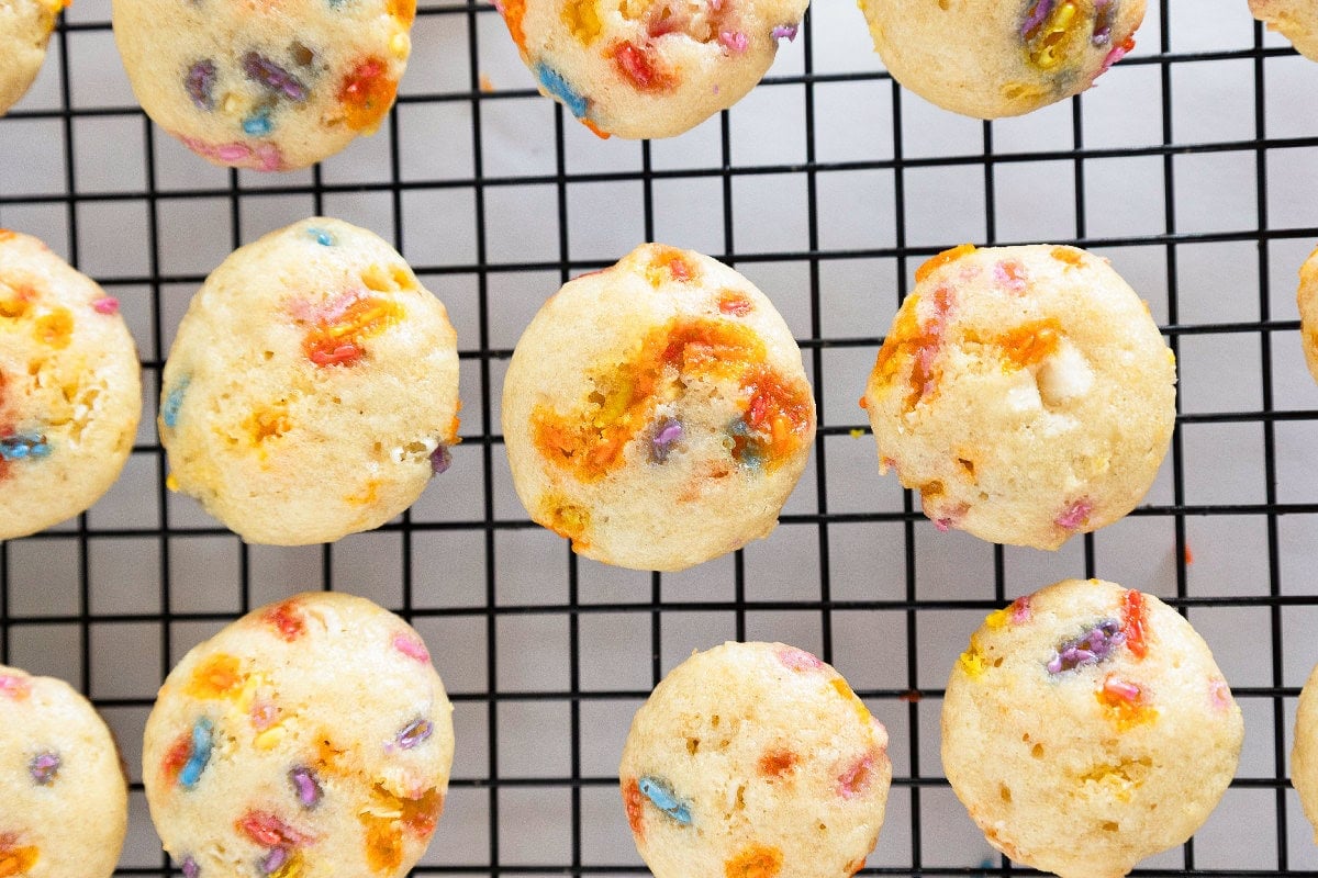 Close-up of birthday cake mini muffins cooling on a wire rack after baking.