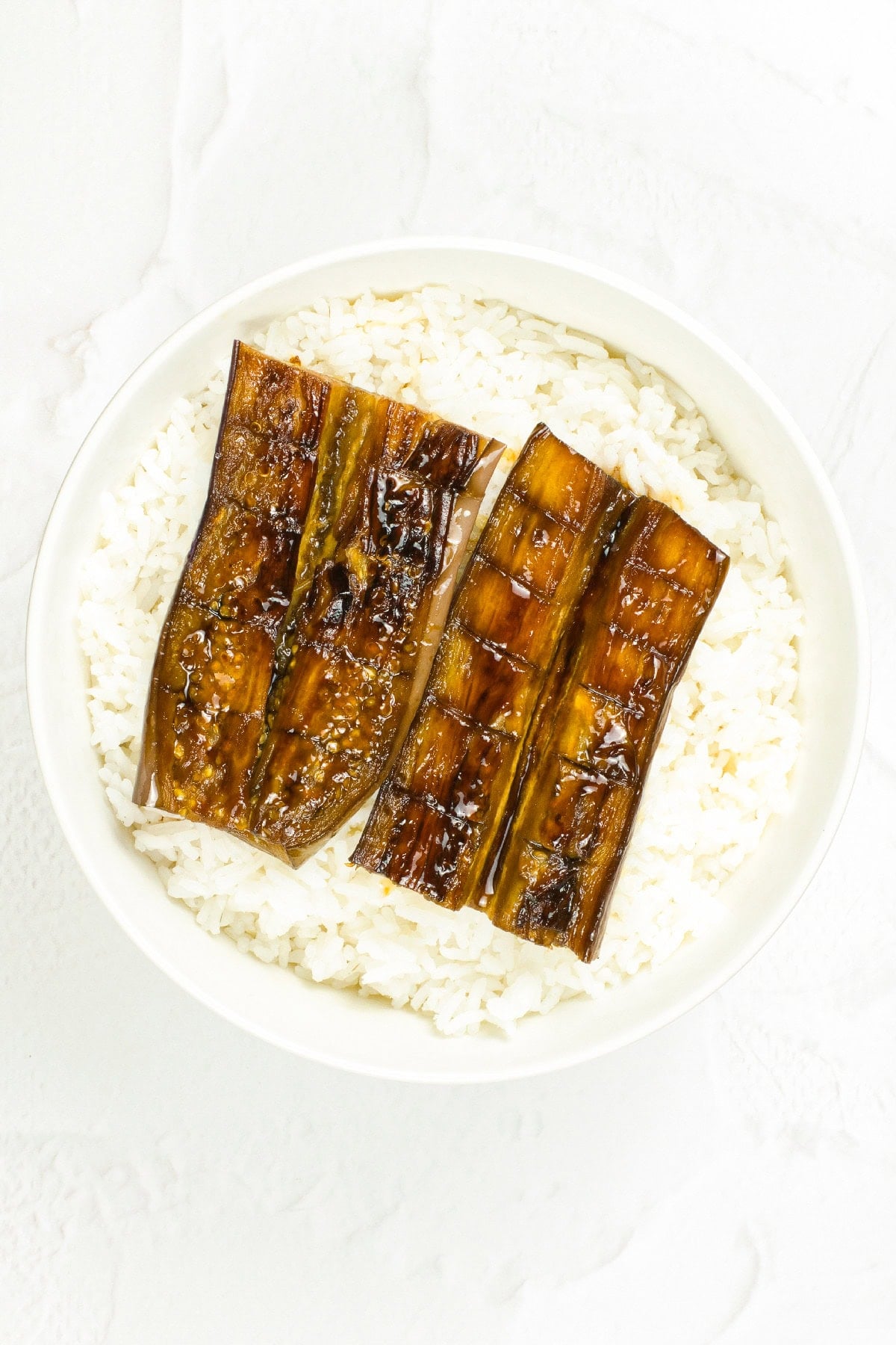 Vegan unagi-style eggplant served over a bowl of steamed white rice.