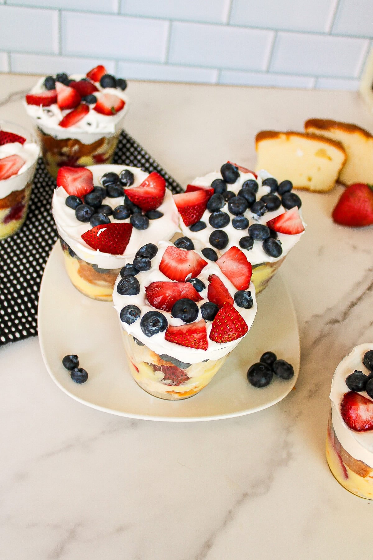 Overhead view of berry parfait cups layered with cake, vanilla pudding, strawberries, blueberries, and whipped topping.