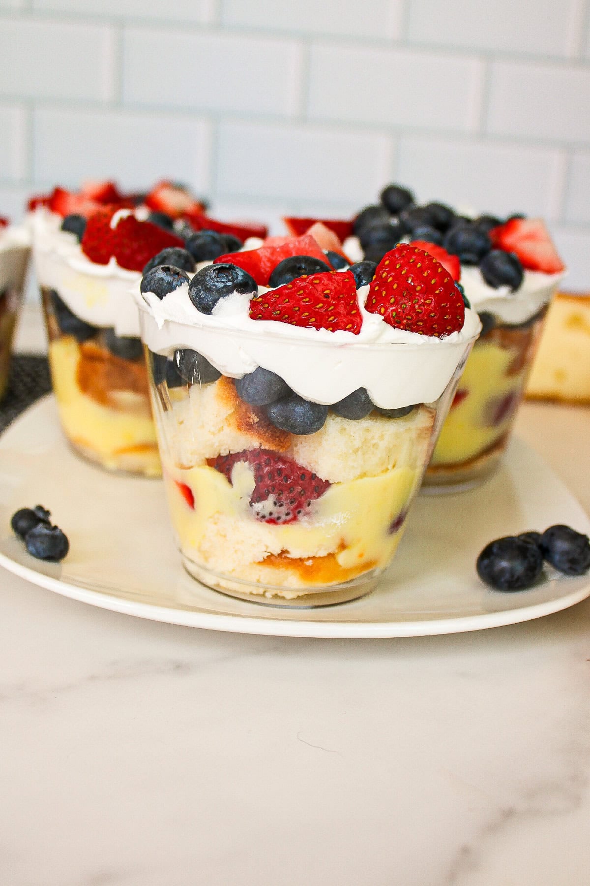 Berry trifle parfait cups with pound cake, vanilla pudding, whipped topping, strawberries, and blueberries.