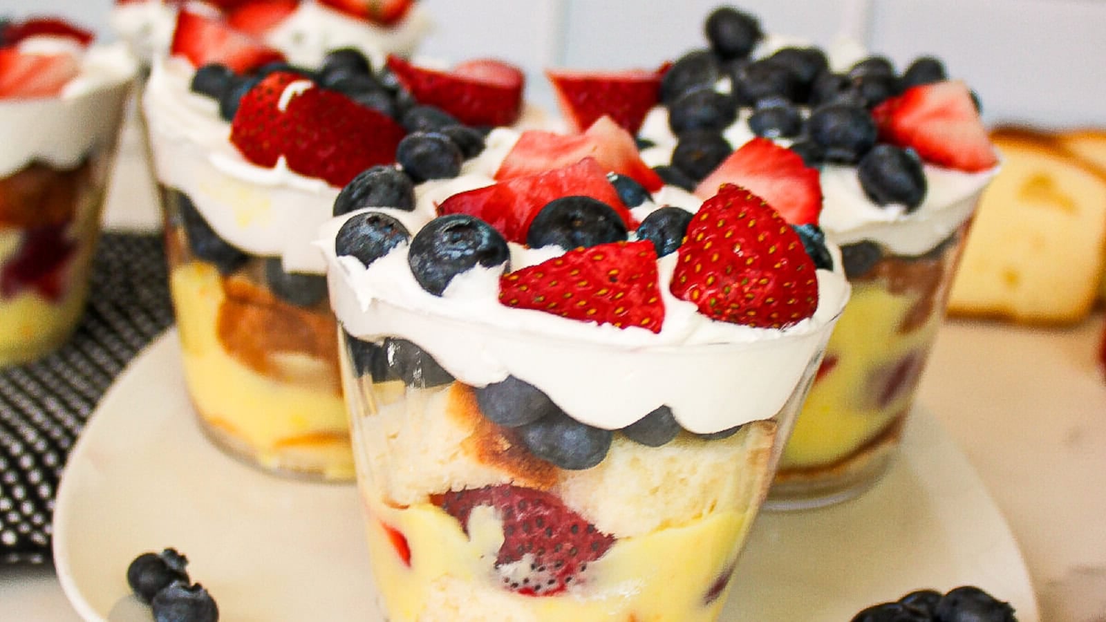 Mini berry parfait cups layered with cake, creamy pudding, whipped topping, strawberries, and blueberries.