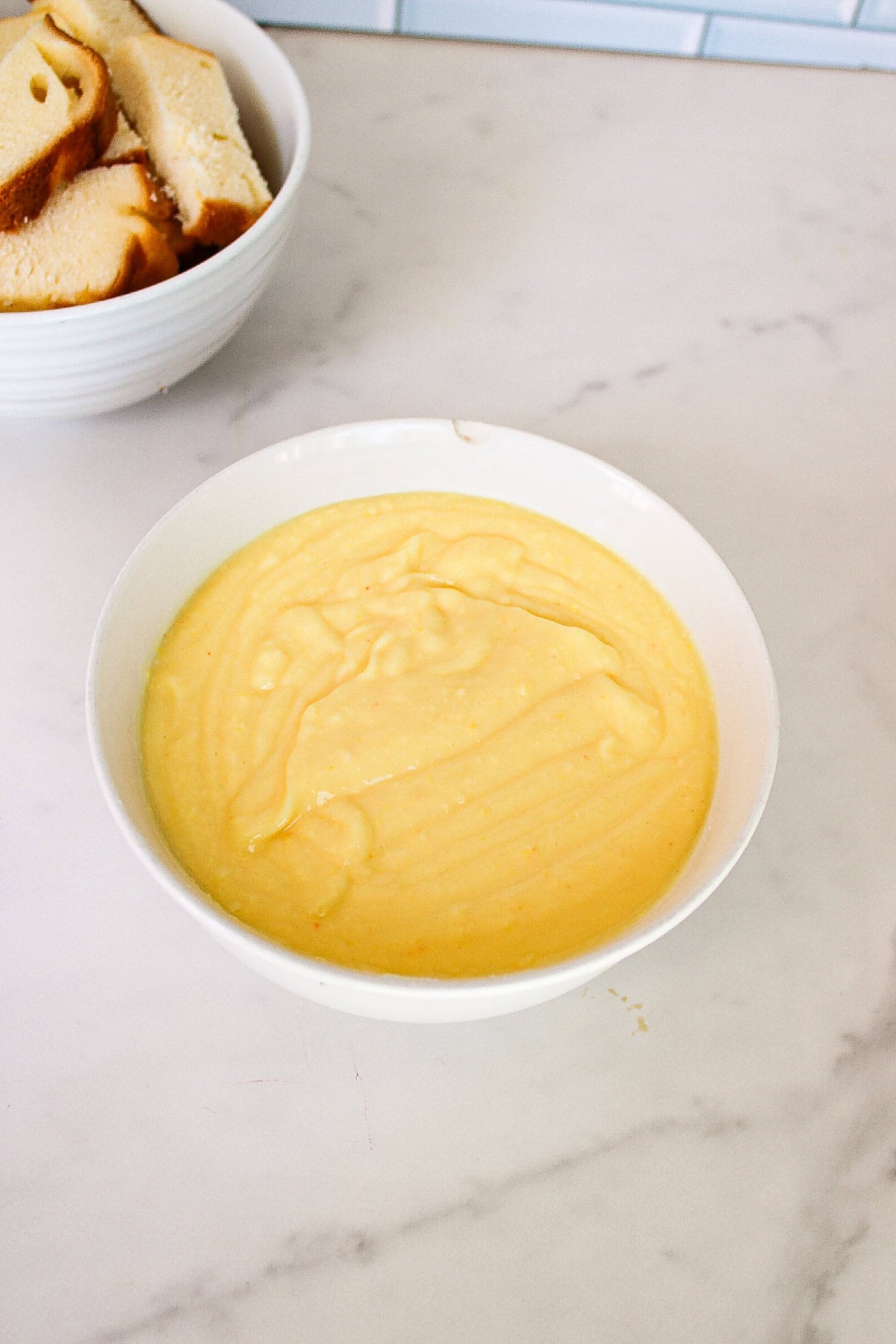 Homemade vanilla pudding in a white bowl ready for layering into parfait cups.