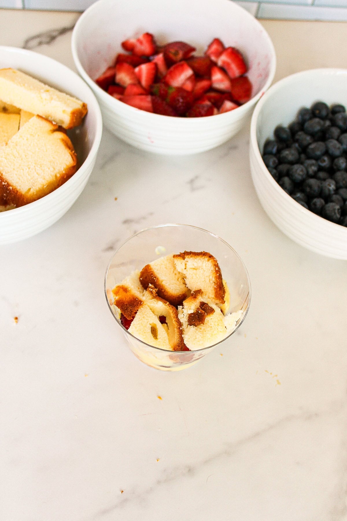 Cubed pound cake added as the second layer in a berry parfait cup dessert.