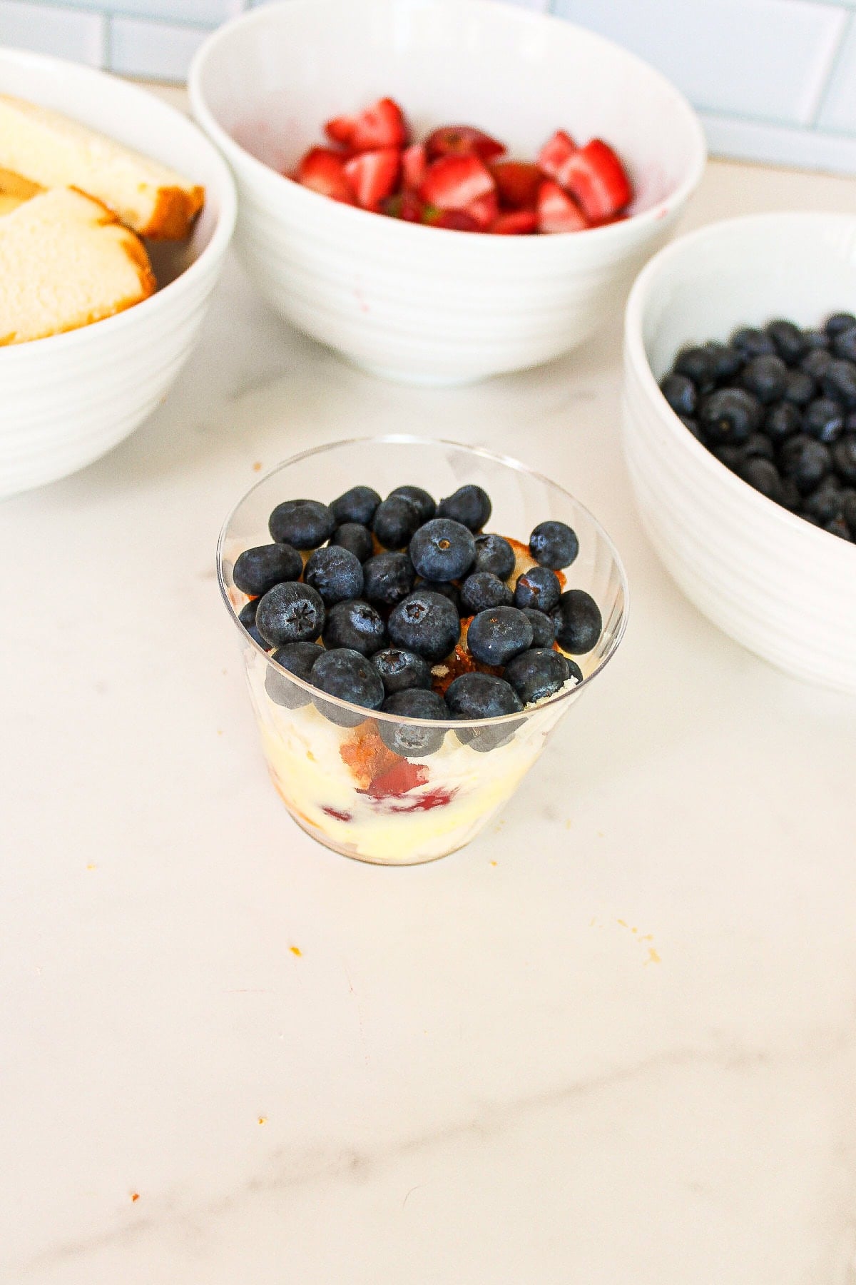 Fresh blueberries layered into a clear parfait cup with cake, pudding, and strawberries.
