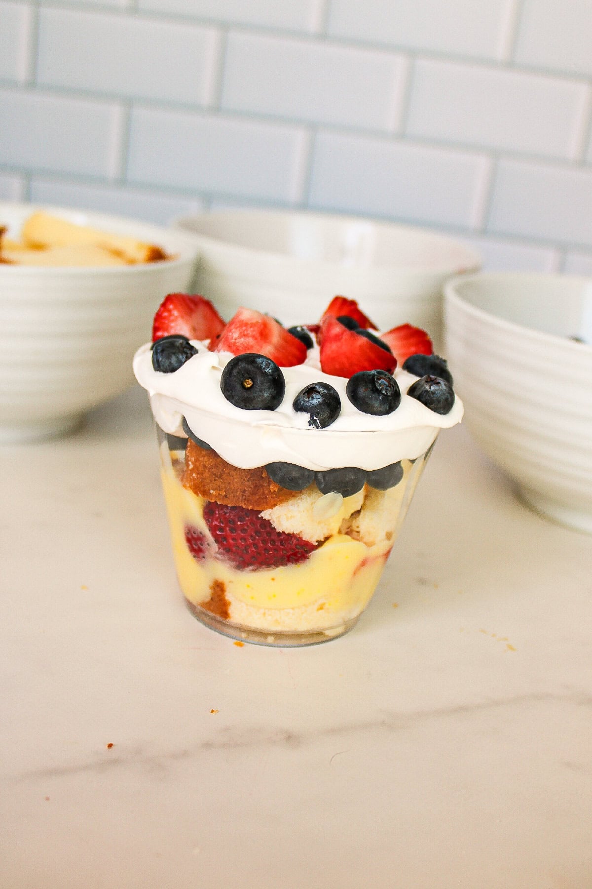 Fresh blueberries layered into a clear parfait cup with cake, pudding, and strawberries.