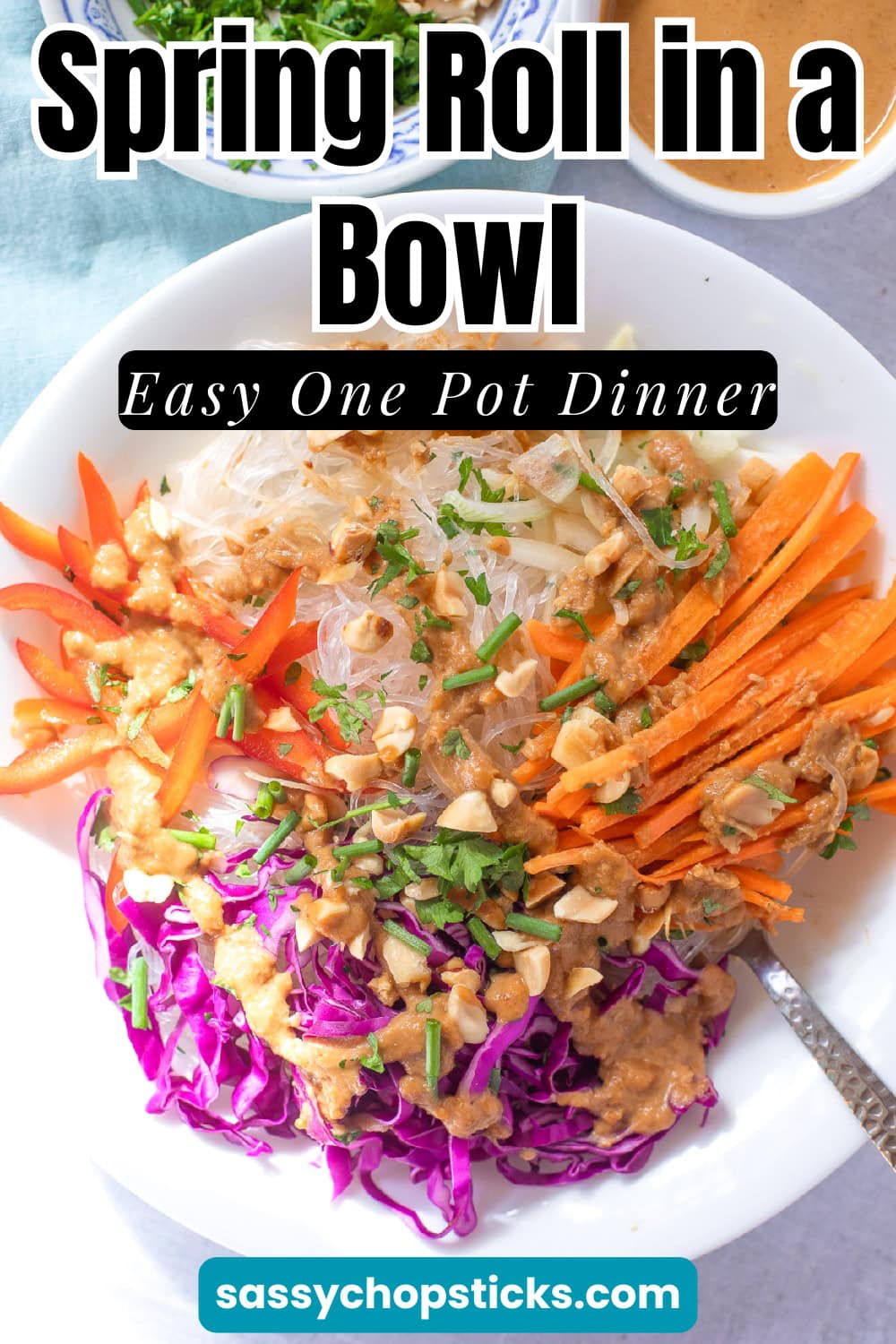 Spring roll in a bowl with rice noodles, red cabbage, carrots, bell peppers, chopped peanuts, and creamy peanut sauce in a bowl.