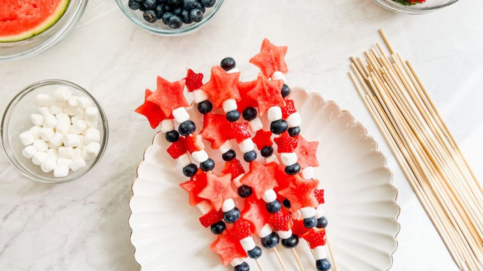 Fruit kabobs threaded with red, white, and blue fruits on skewers.