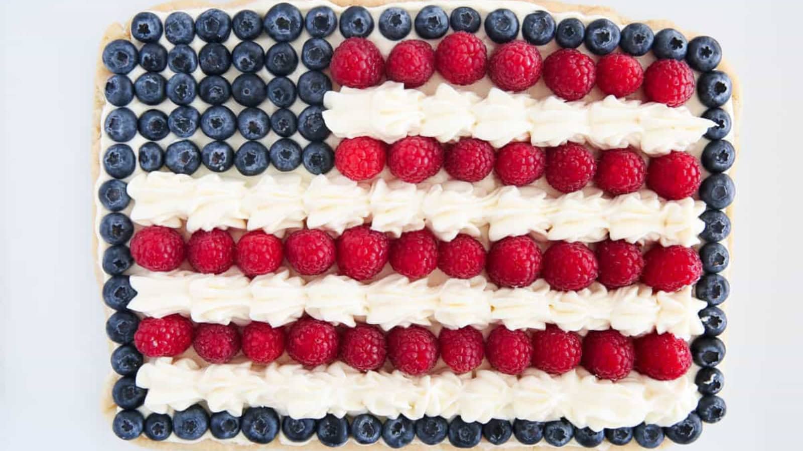 Fruit pizza topped with cream cheese frosting and colorful fresh fruit.