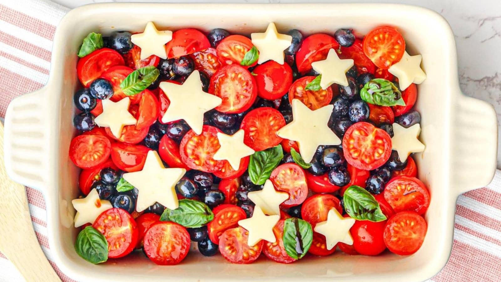 Caprese salad topped with berries, cheese, and fresh basil.