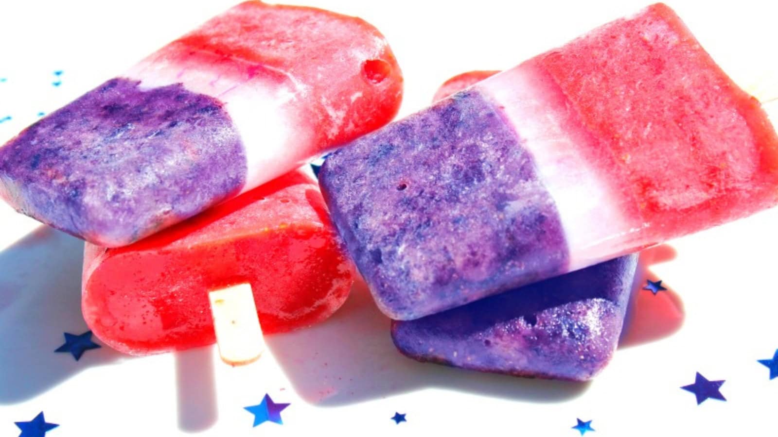 Homemade bomb pops with colorful fruit layers frozen on popsicle sticks.