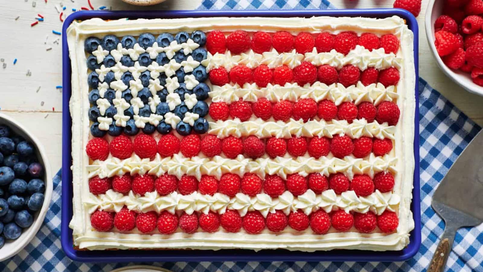 Patriotic flag cake decorated with strawberries, blueberries, and frosting.