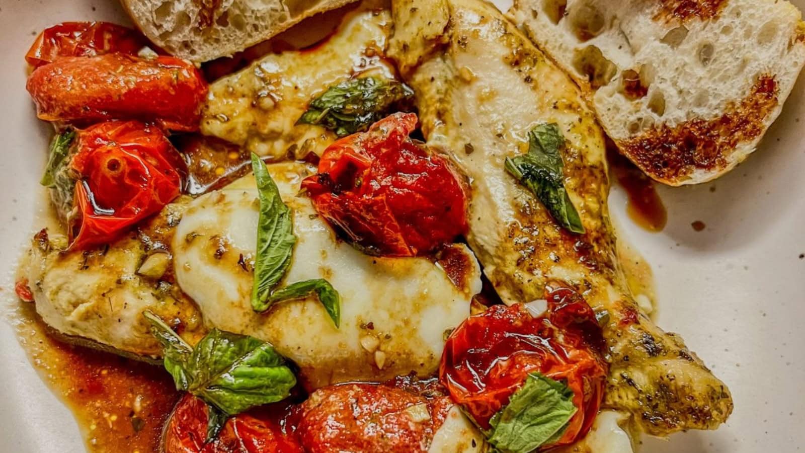 Sheet pan chicken baked with tomatoes, mozzarella, and basil.
