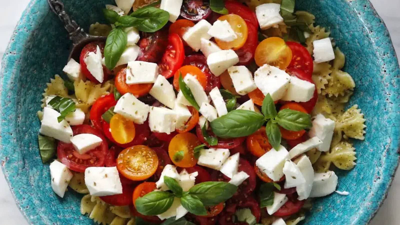 Pasta salad mixed with tomatoes, mozzarella, and basil.