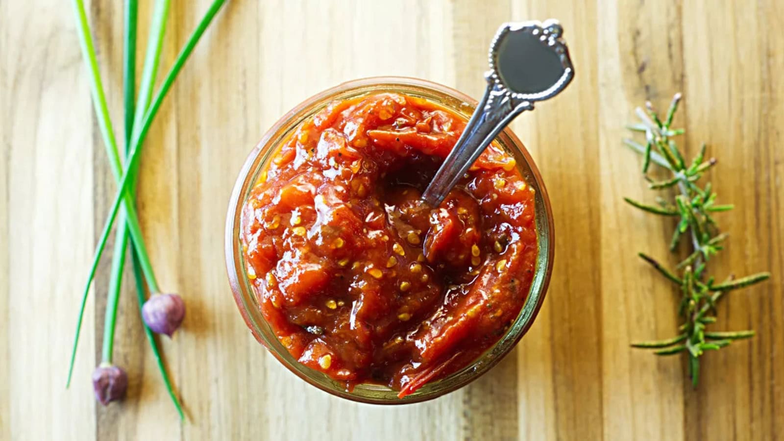 Homemade cherry tomato jam served in a jar with a glossy texture.