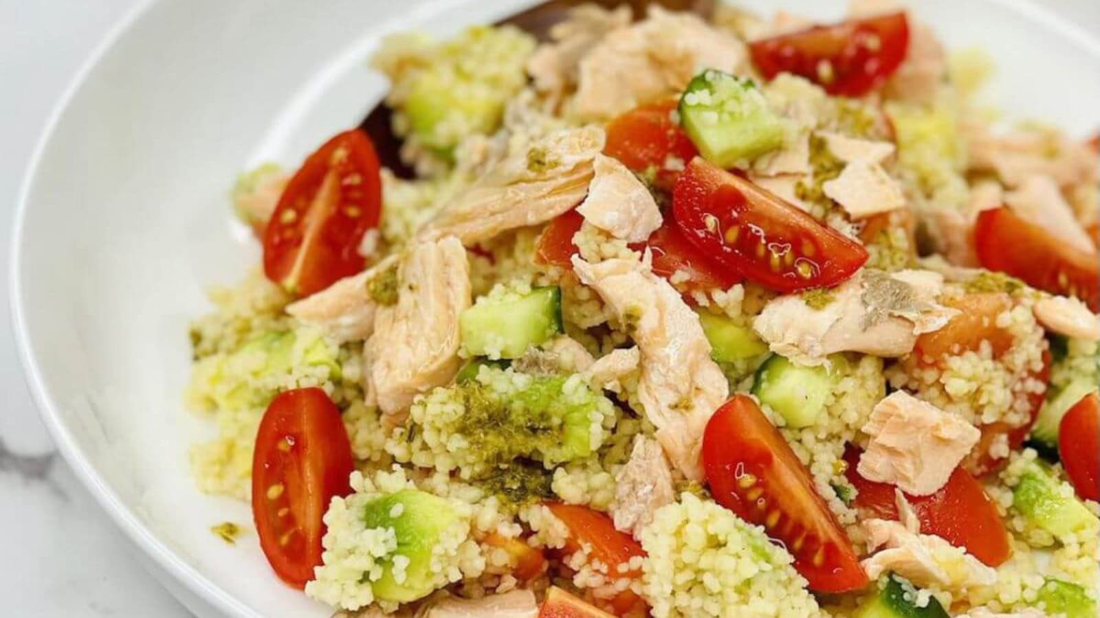 Couscous salad with salmon, fresh vegetables, and herbs.