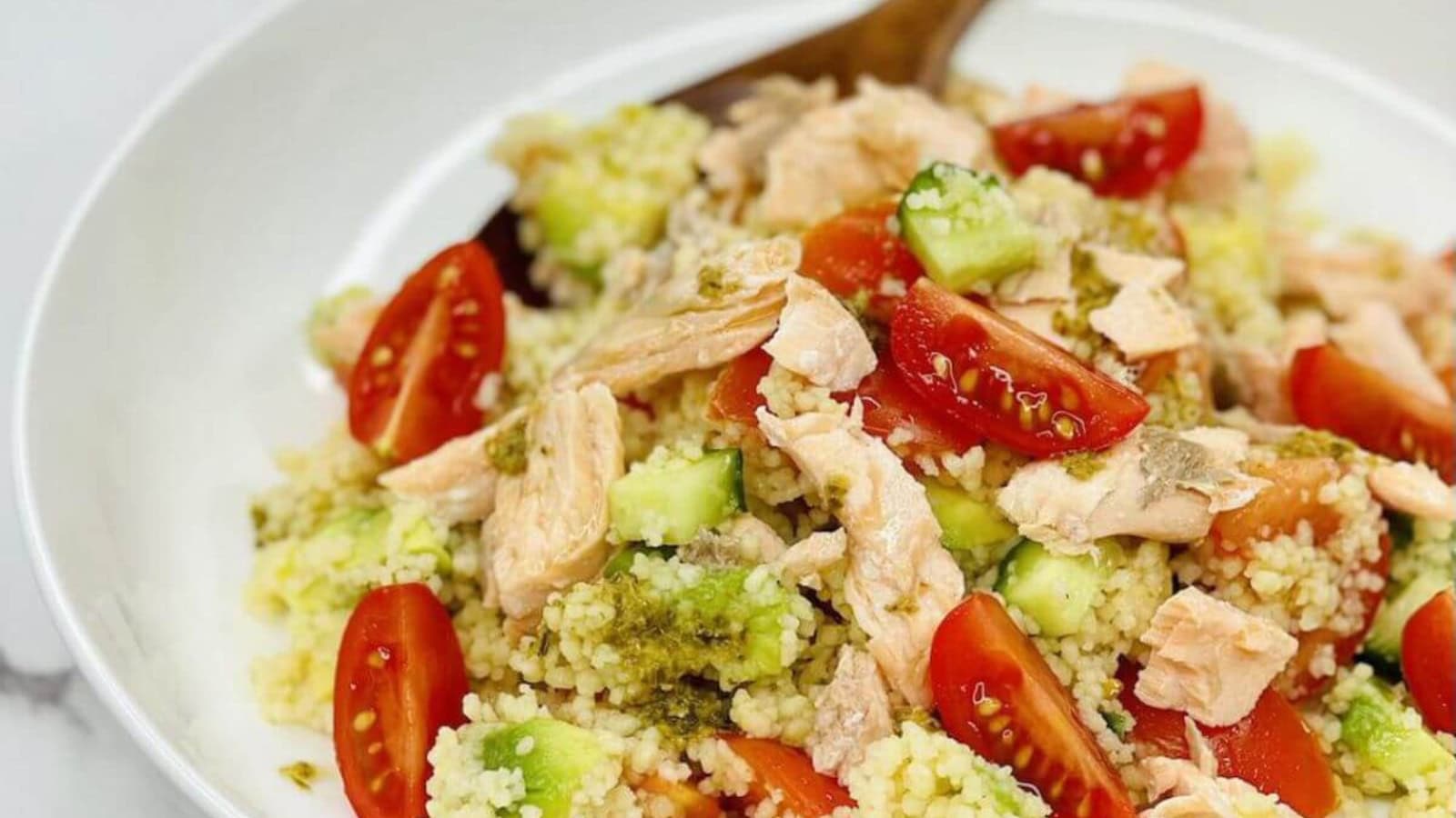 Couscous salad topped with salmon and fresh vegetables.