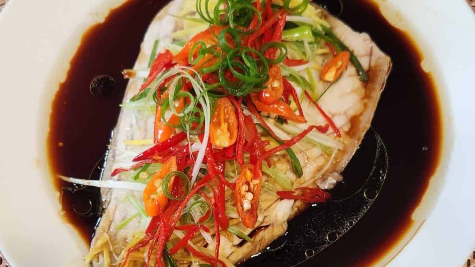 Cantonese-style steamed fish garnished with ginger and scallions.