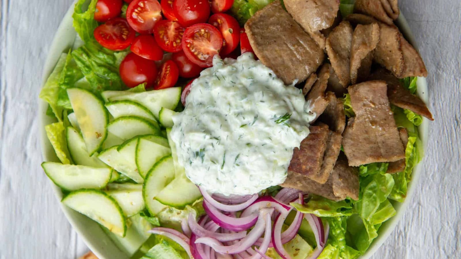 Greek gyro salad with seasoned meat, vegetables, and feta cheese.