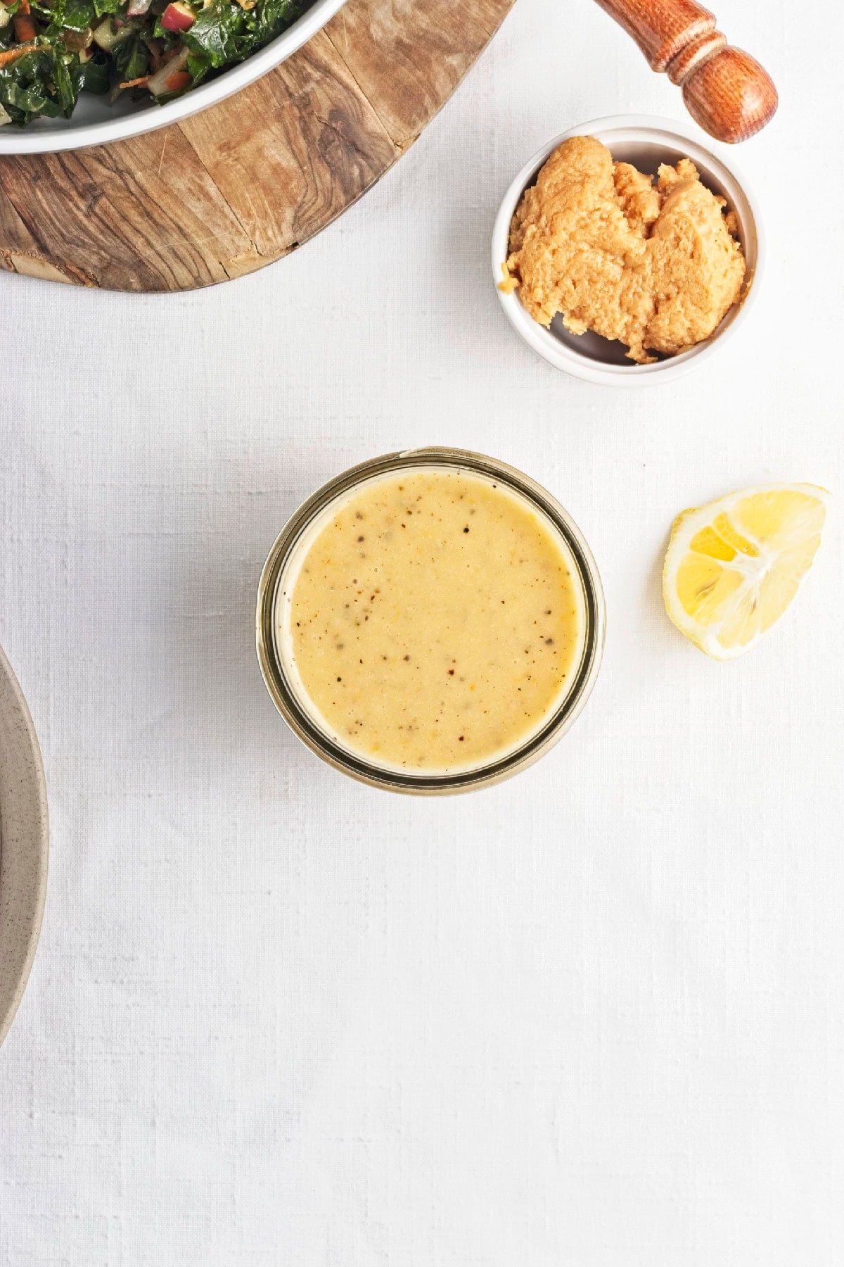 Creamy homemade lemon miso dressing in a glass jar with miso paste and fresh lemon.