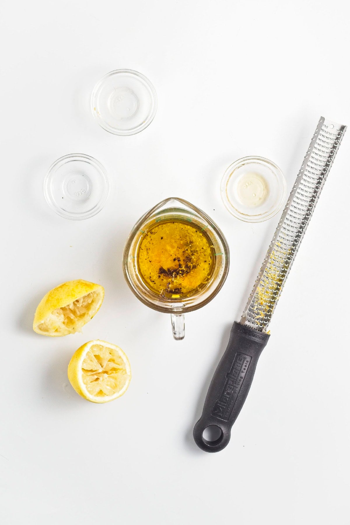Lemon miso dressing ingredients in a measuring cup with fresh lemon and a microplane zester.