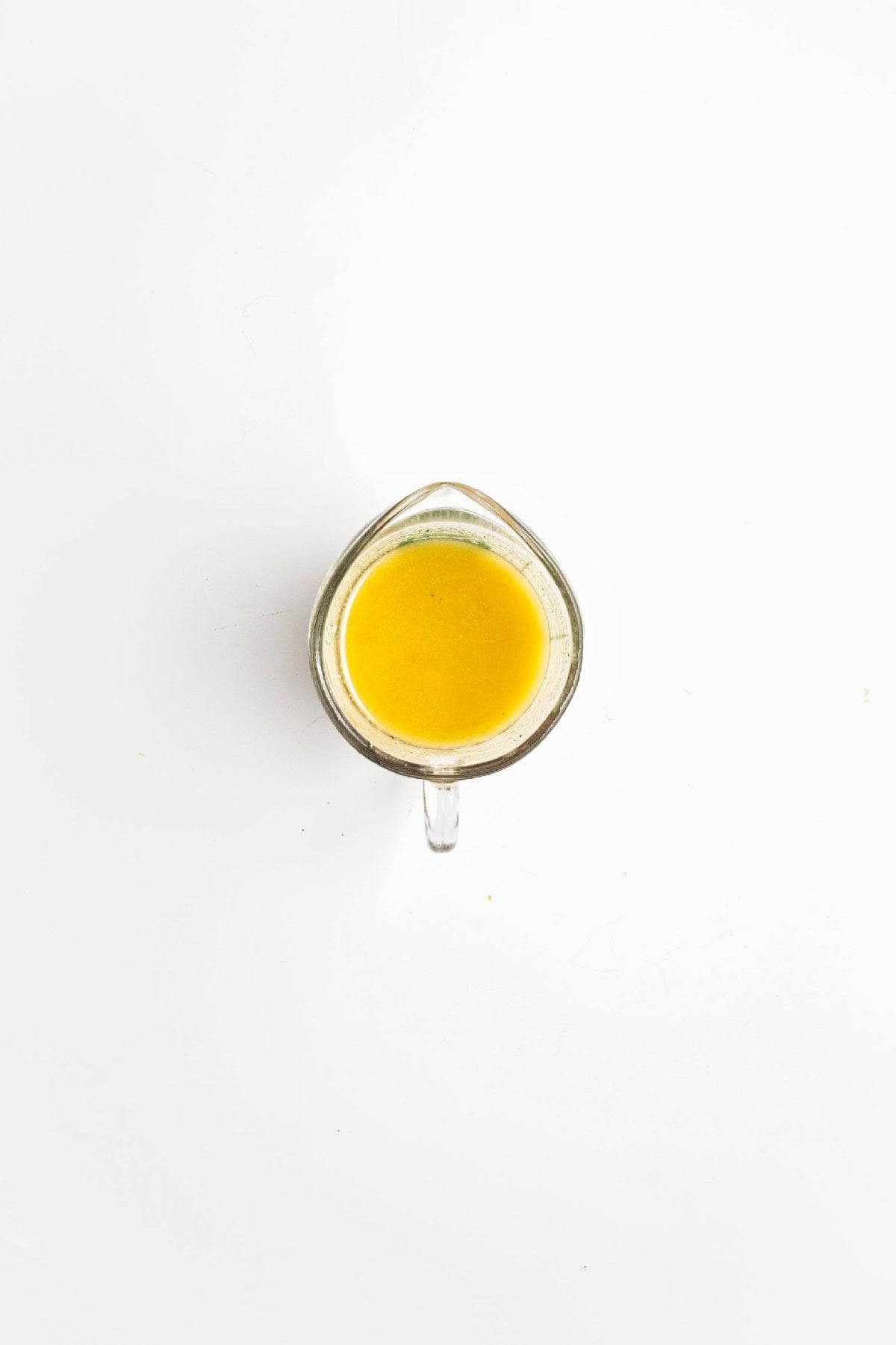 Lemon miso dressing ingredients combined in a glass measuring cup before mixing.