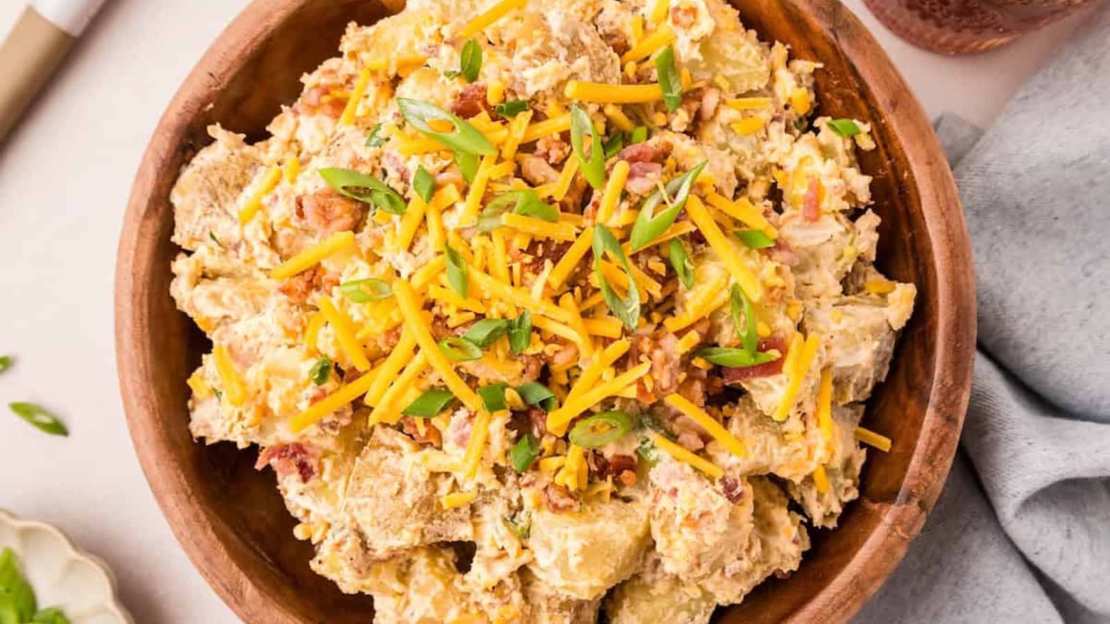 Potato salad topped with cheese, bacon, and creamy dressing.