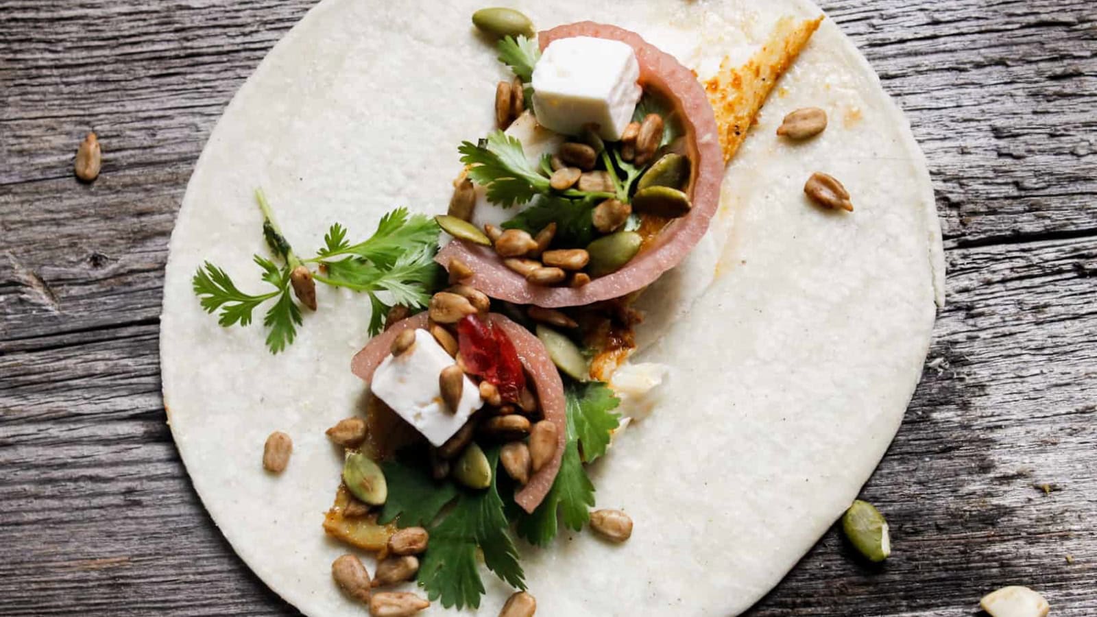 Fish tacos topped with fresh slaw and colorful garnishes.