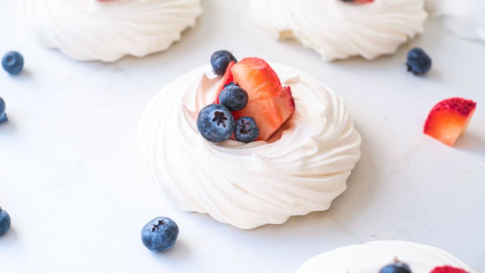 Mini pavlovas topped with whipped cream and fresh patriotic berries.