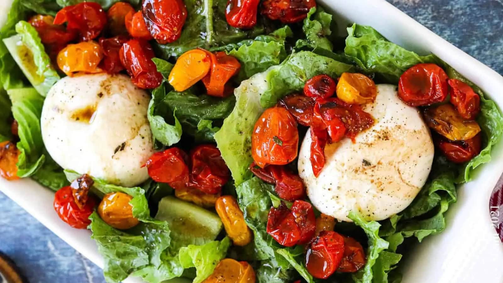 Roasted tomato salad topped with creamy burrata cheese and herbs.