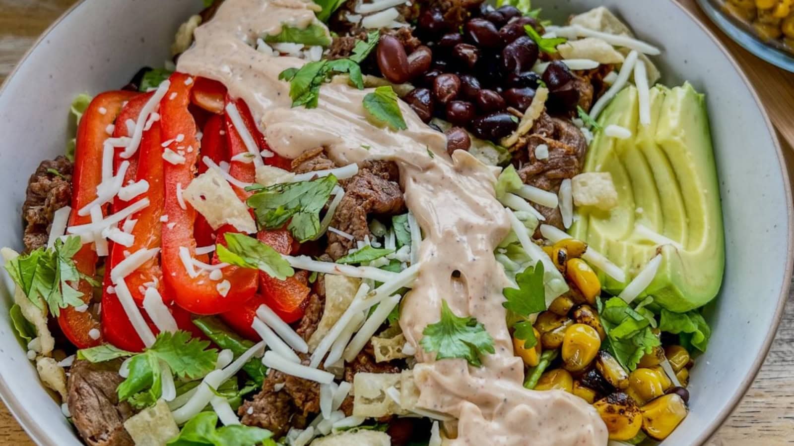 Steak salad topped with southwest-inspired vegetables and dressing.