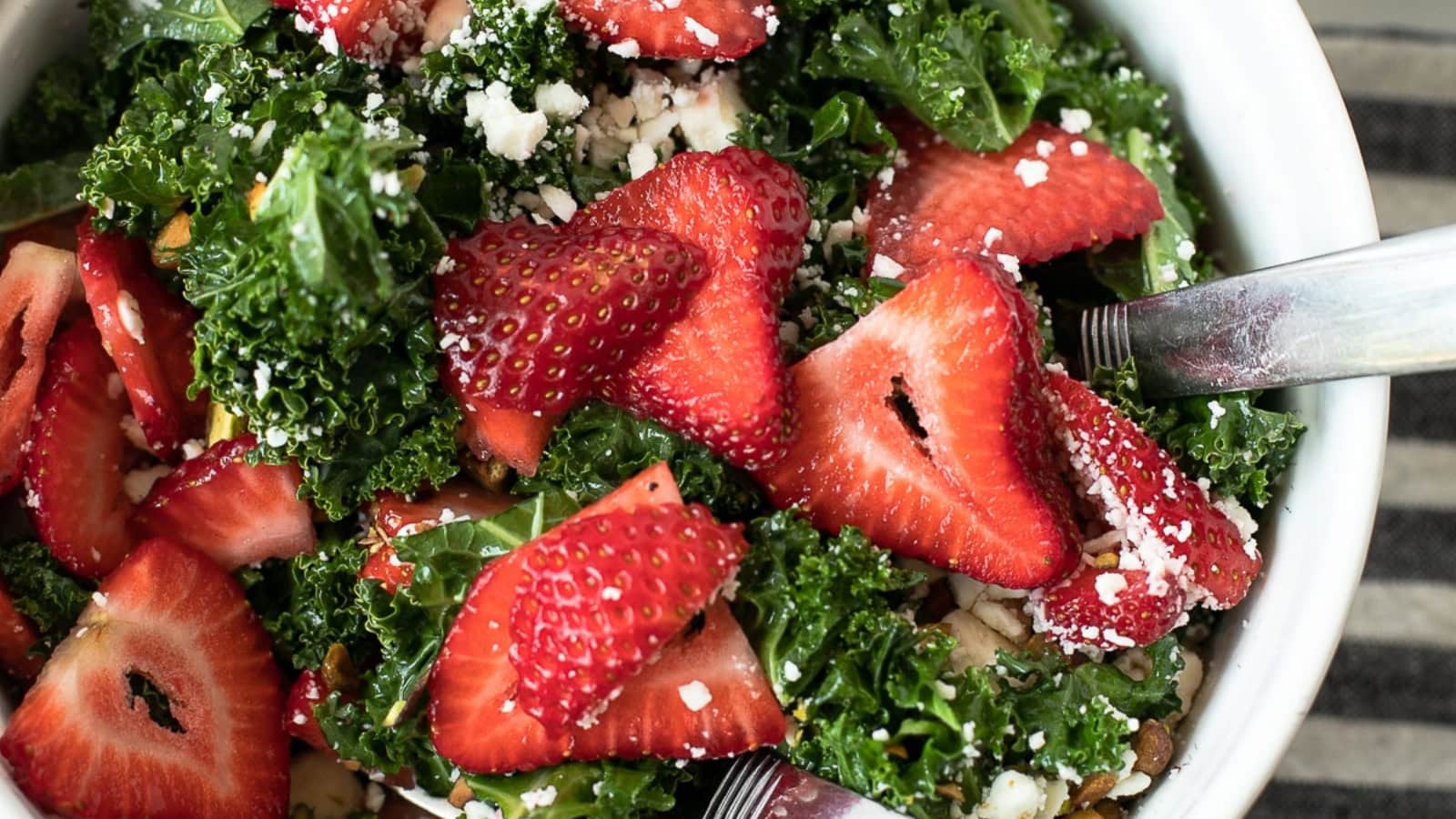 Kale salad topped with strawberries and fresh ingredients.