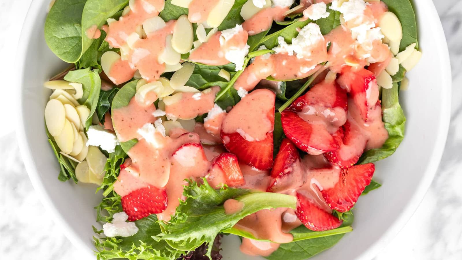 Spinach salad tossed with strawberries and sliced almonds.