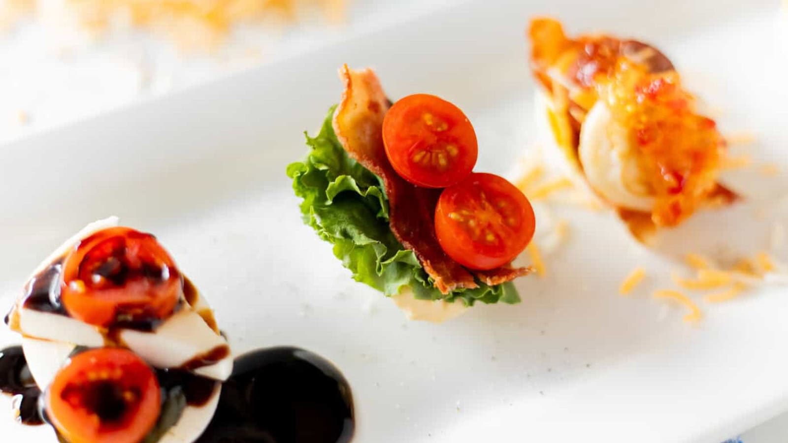 Assorted egg flight appetizers topped with BLT, chicken salad, and Caprese ingredients.