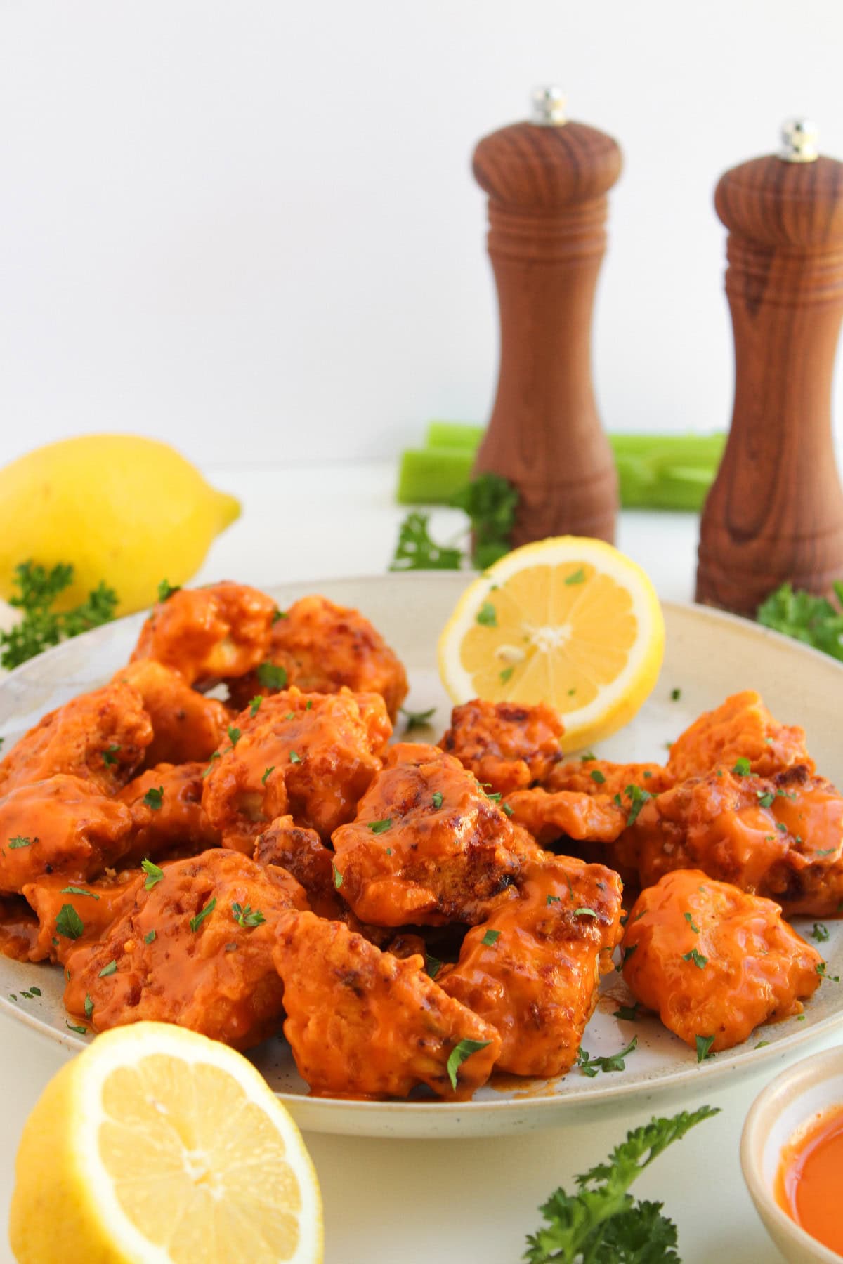 Boneless buffalo wings plated with lemon wedges, celery sticks, and buffalo dipping sauce.