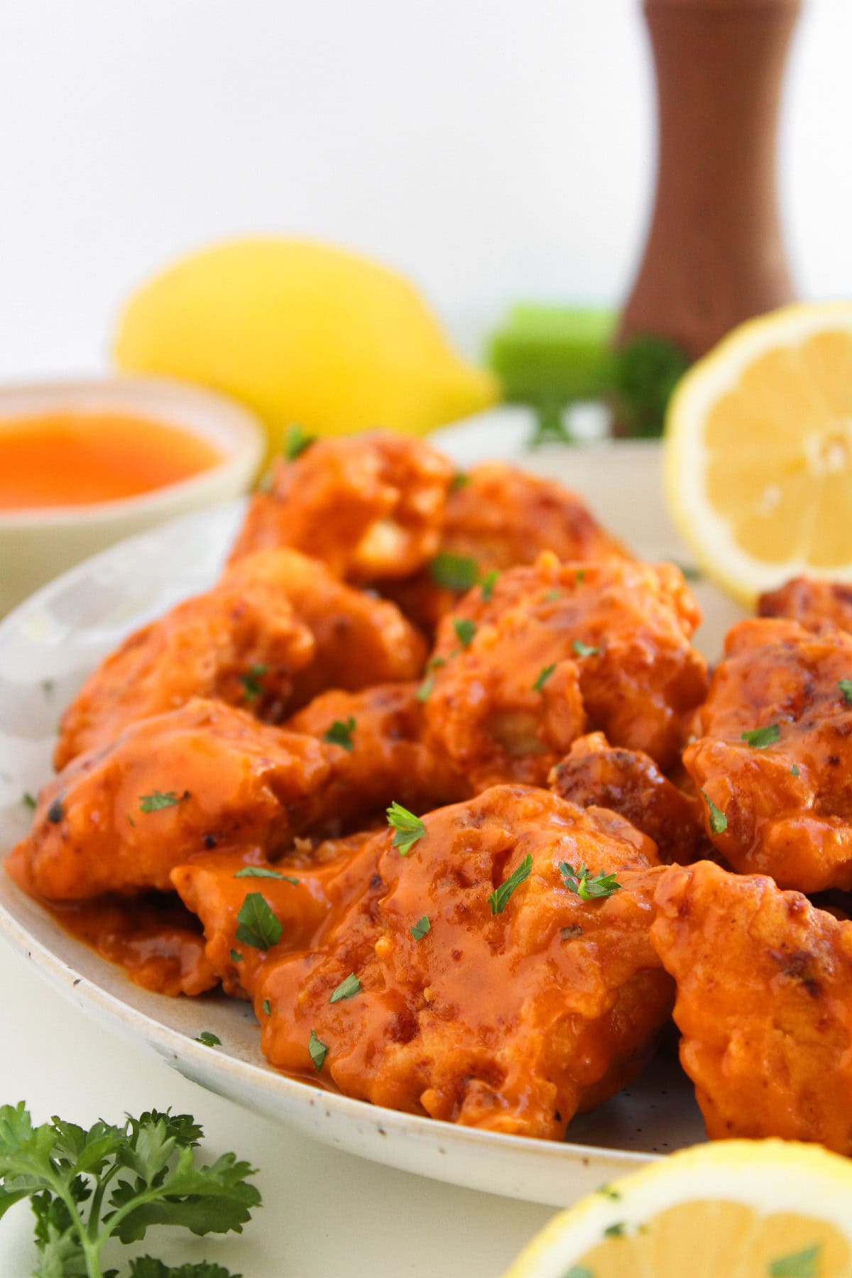 Side view of crispy boneless buffalo wings covered in buffalo sauce on a serving plate.