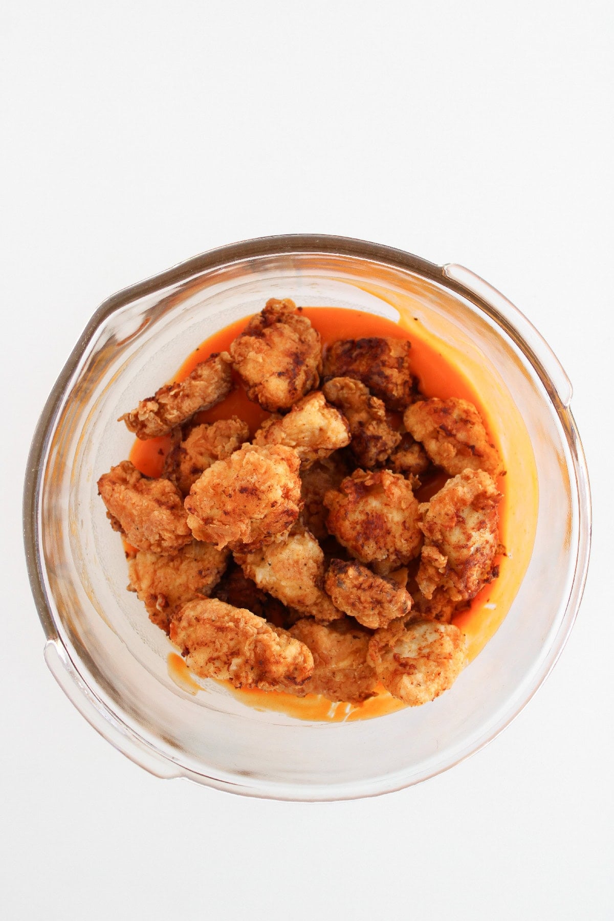 Crispy boneless buffalo wings added to buffalo sauce before tossing.