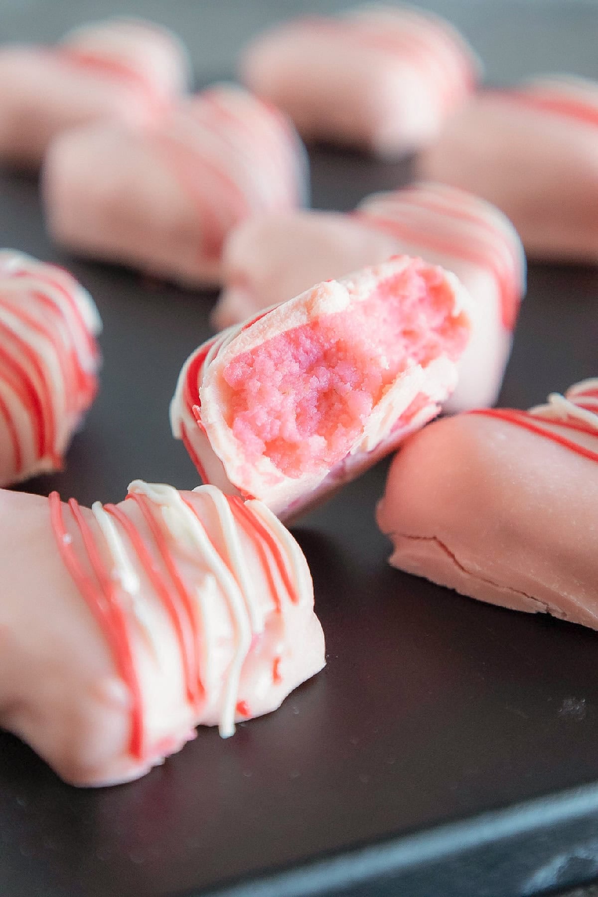 Close-up of a cut-open pink cake truffle revealing the soft cake filling and candy shell.