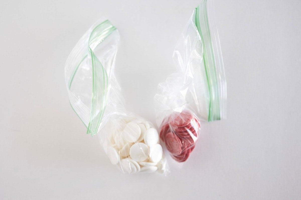 White and red candy melts portioned into small plastic bags for decorating cake truffles.