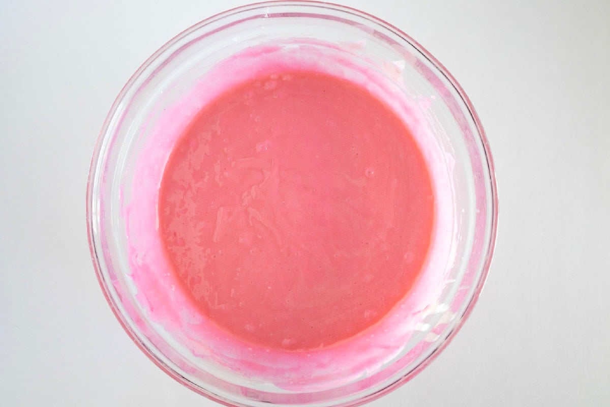 Pink cake batter is mixed until evenly colored.