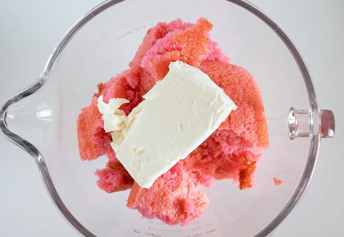 Crumbled pink cake and cream cheese in a mixing bowl for cake truffles.
