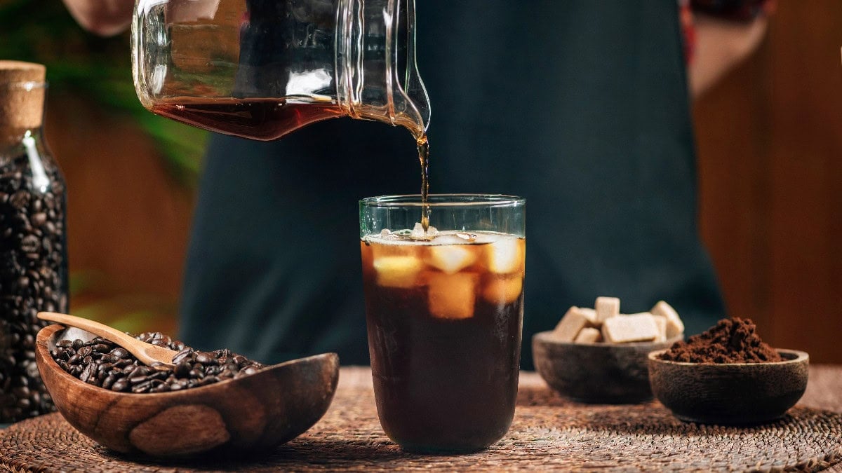 Fresh cold brew coffee being poured into a glass over ice.